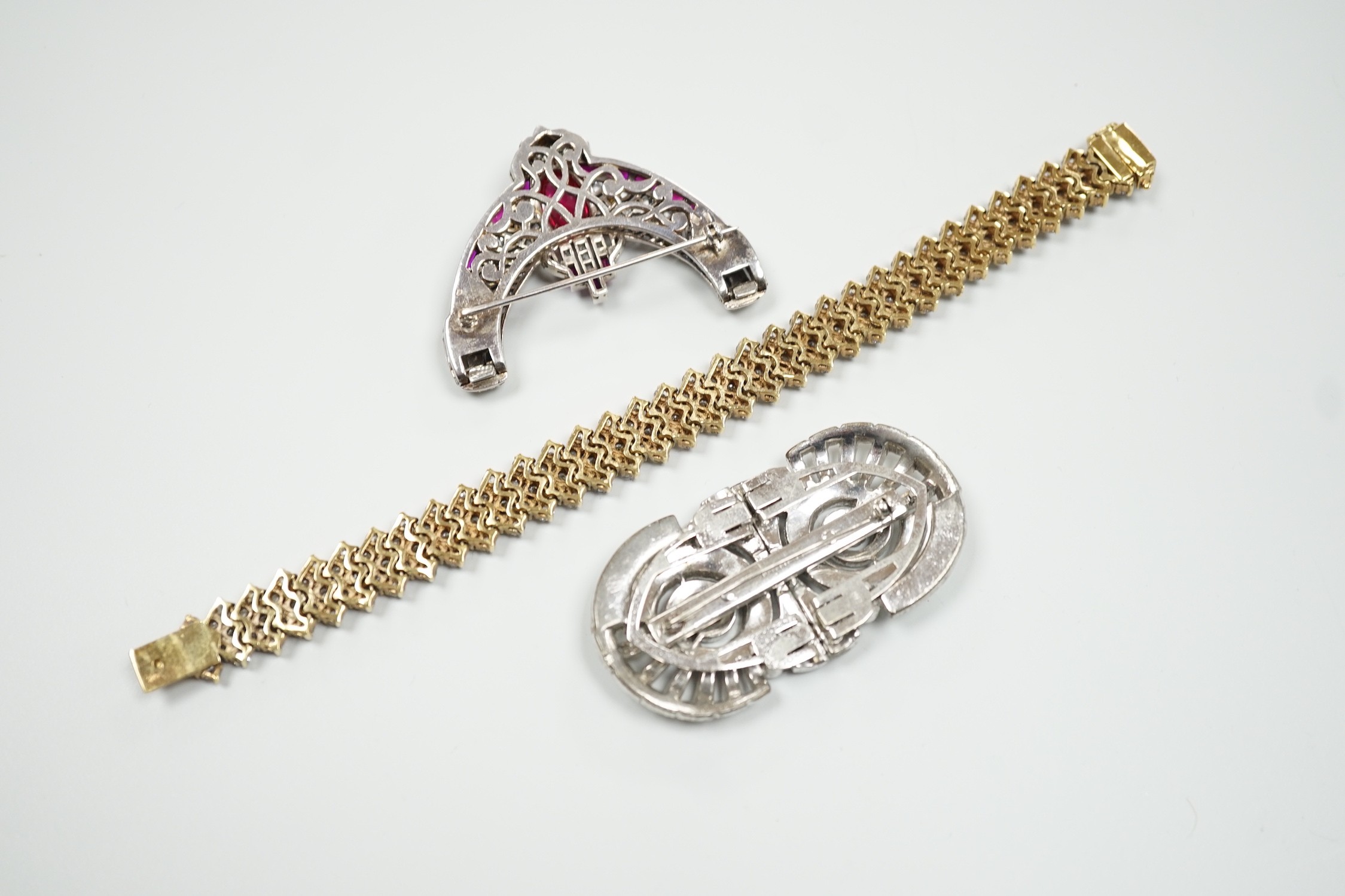 An Art Deco style white metal and two colour paste set curved clip brooch, width 56mm, a paste set double clip brooch, width 65mm and and a similar paste set gilt 925 bracelet, 18.5cm.